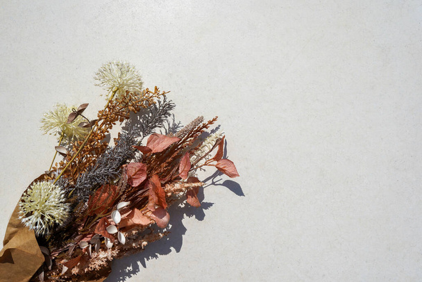 Een ruiker van gedroogde bloemen in ambachtelijk papier op een witte achtergrond met kopieerruimte - Foto, afbeelding