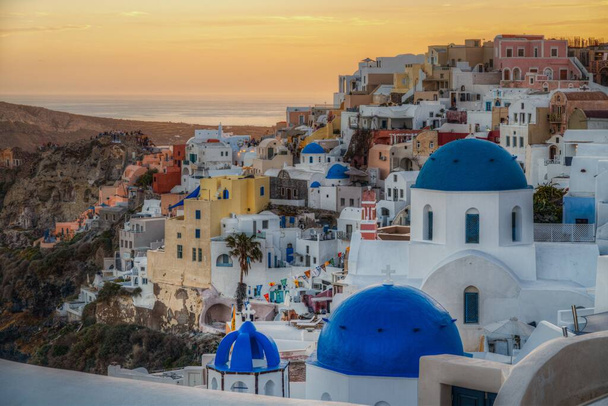 Scenic panoramic view of Oia village at sunset with the iconic blue domed church in the foreground, Santorini, Greece - Fotoğraf, Görsel