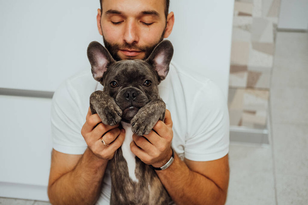 Happy Caucasian Man Hugging His Lovely Pet Small French Bulldog - Foto, afbeelding