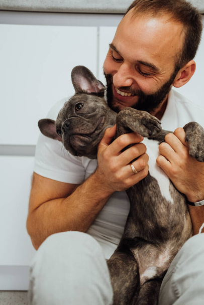 Cheerful Caucasian Man Hugging His Lovely Pet Small French Bulldog - Fotoğraf, Görsel