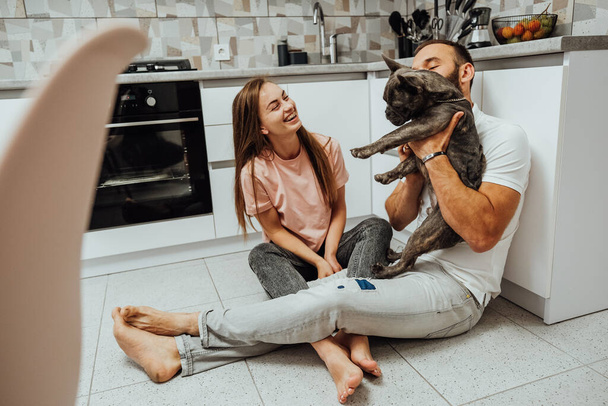 Cheerful Woman and Man Having Fun Time at Kitchen with Their Dog, French Bulldog with Family at Home - Fotoğraf, Görsel