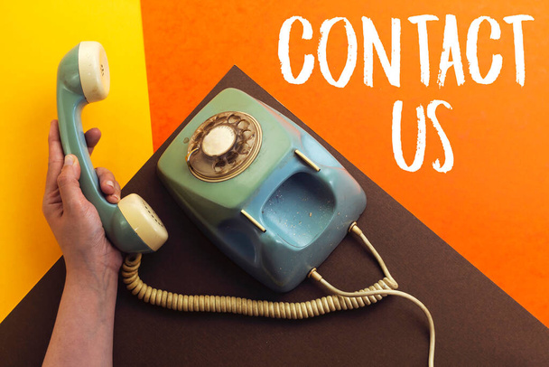 old retro phone and hand holding handset with contact us concept  - Valokuva, kuva
