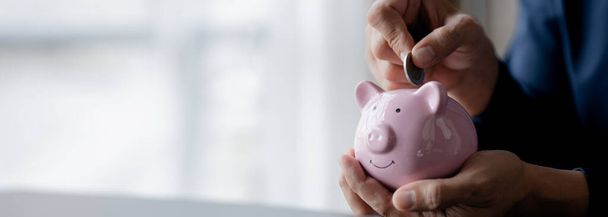 A businessman holding a coin in a piggy bank. Placing coins in a row from low to high is comparable to saving money to grow more. The concept of growing savings and saving by investing in stock funds. - Fotoğraf, Görsel