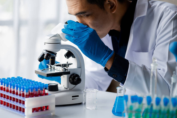 Laborassistenten untersuchen chemische Reaktionen, Mediziner, Chemiker, chemische Experimente und Krankheitstests aus Blutproben von Patienten. Medizin und Forschungskonzept - Foto, Bild