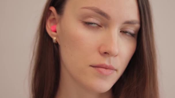 A young brunette woman takes earplugs out of her ear. Noise protection - Filmati, video