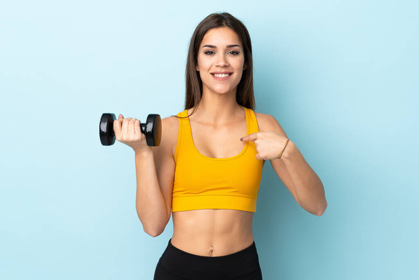 Young caucasian woman making weightlifting isolated on blue background with surprise facial expression - Foto, Bild