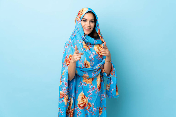 Young Moroccan woman with traditional costume isolated on blue background pointing to the front and smiling - Foto, Bild