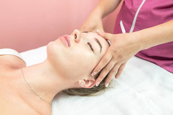 Beautiful girl doing facial massage in beauty clinic - Fotografie, Obrázek