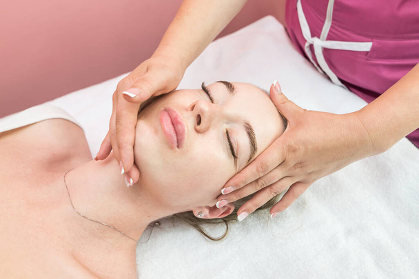 Beautiful girl doing facial massage in beauty clinic - Fotó, kép