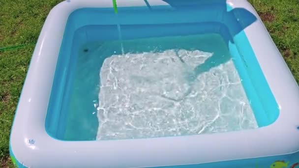 Blick auf das Kinderschwimmbecken, das an warmen Sommertagen mit Wasser aus dem Gartenschlauch gefüllt wird. Schweden. - Filmmaterial, Video