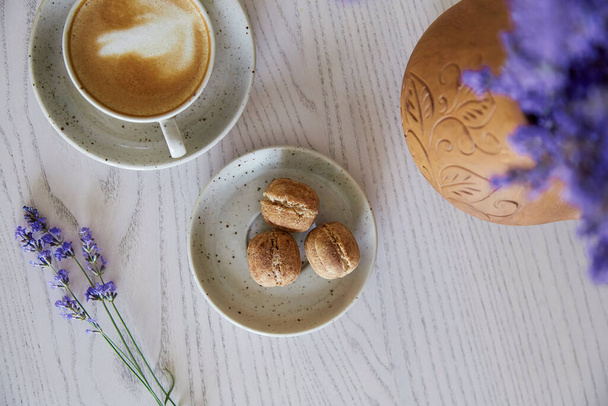  Vegan natural nuts sweets with no sugar. Cup of cappuccino on wooden table in the cafe. Natural sweets. Coffee break. Lavender decorations - Foto, Bild
