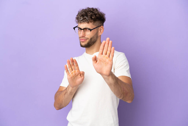 Delivery caucasian man isolated on purple background nervous stretching hands to the front - 写真・画像