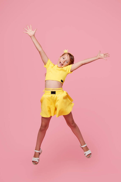 Full length portrait of cheerful triumphant child girl jump up raise fists good mood isolated on pink color background - Zdjęcie, obraz