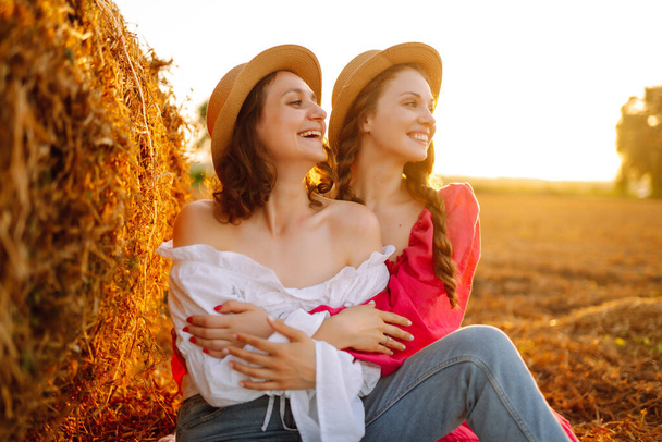 Two young woman near haystack at sunset. Fashion concept. Beautiful figures. Super mood. Summer concept. - Foto, imagen