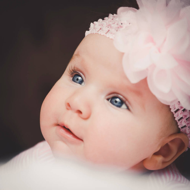 Close-up portrait of cute 3 months old smiling baby girl in pink. Big open eyes. Healthy little kid shortly after birth - Photo, Image