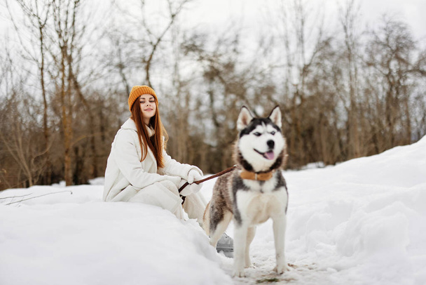 Szczęśliwa młoda kobieta w śniegu bawiąca się z psem na świeżym powietrzu przyjaźń. Wysokiej jakości zdjęcie - Zdjęcie, obraz