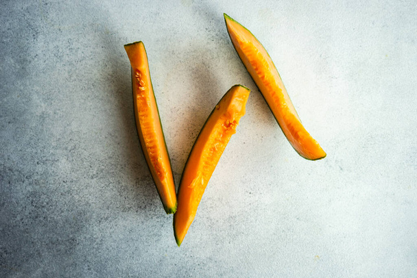 Ripe cantaloupe melon slices on minimalistic concrete background - Valokuva, kuva