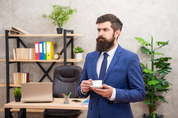 serious mature entrepreneur in jacket having coffee break at office, business. - Фото, изображение