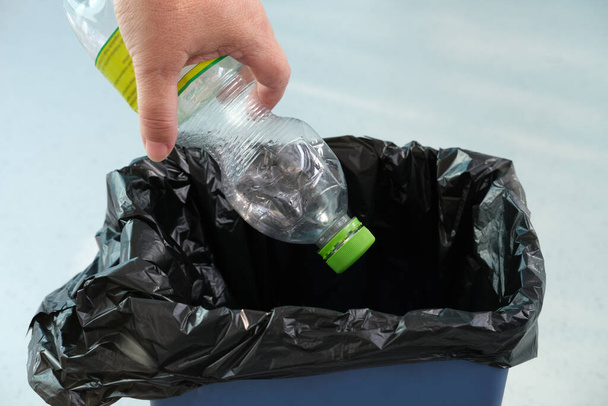 woman puts an empty plastic bottle in a recycling bin, close-up hands, the concept of household waste disposal, different types of garbage into different bins, waste recycling, reuse - Fotó, kép