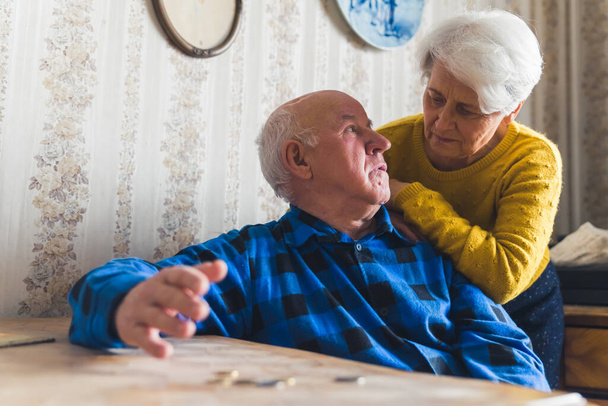 Sad, lost and worried caucasian senior couple counting their last coins while sitting at the table. Financial Crisis. Low pension. High quality photo - Photo, Image