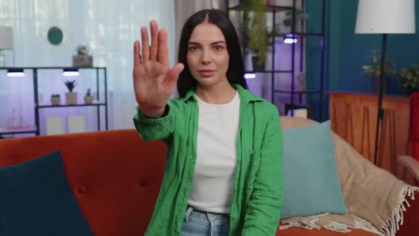 Stop gesture. Angry girl say No hold palm folded crossed hands, warning of finish, prohibited access, declining communication, body language, danger. Young woman at home room sitting on sofa indoors - Materiał filmowy, wideo