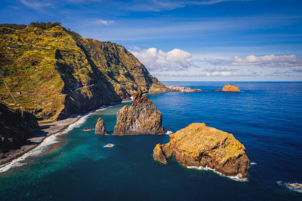 View of the Ilheus da Ribeira da Janela rock islets under a clear blue sky. The rocks form a famous landmark on the northern shore of the island of Madeira, Portugal. Aerial drone shot, october 2021 - Valokuva, kuva