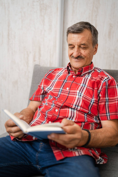 Один чоловік старший кавказький чоловік з вусами читає книгу вдома в червоній сорочці реальні люди дозвілля концепція копіювання простору
 - Фото, зображення