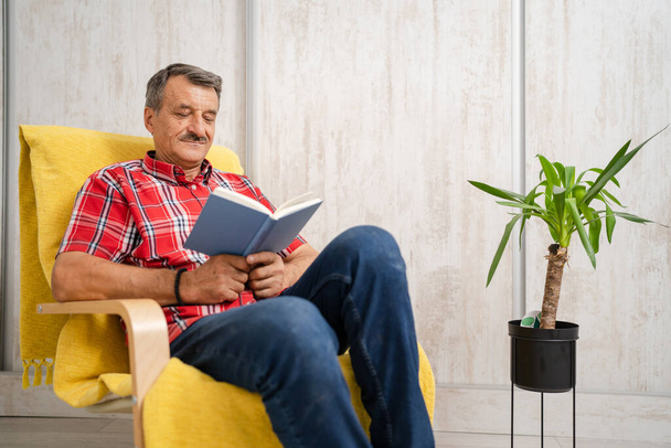 One man senior caucasian male with mustaches read book at home wear red shirt real people leisure concept copy space serious person - Photo, Image