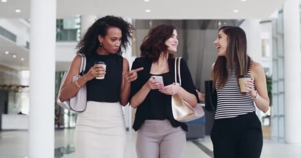 Female business women talking, chatting and checking social media on phone while walking inside an office. Laughing, smiling and cheerful colleagues gossiping and enjoying their coffee break together. - Imágenes, Vídeo