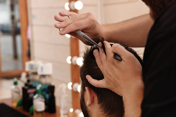Professional hairdresser working with client in barbershop, closeup - Fotografie, Obrázek