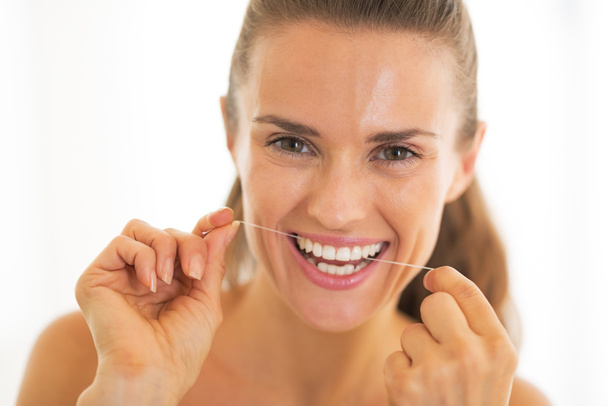 Portrait of young woman using dental floss - Foto, afbeelding