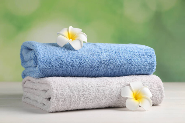 Soft folded towels and plumeria flowers on white wooden table - Fotografie, Obrázek