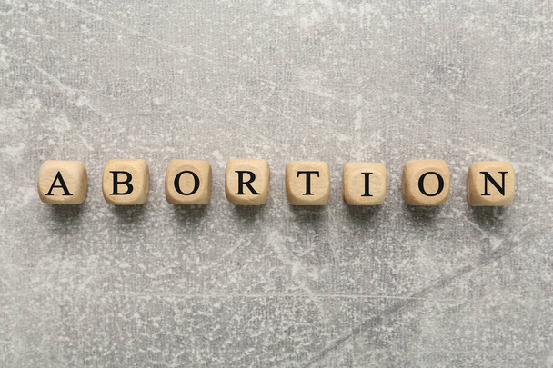 Word Abortion made of wooden cubes on grey background, flat lay - Foto, imagen