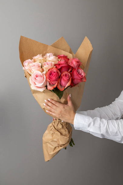hands holding a bouquet of colorful roses, flower arrangement as a romantic gift, studio with detail in the petals, beauty of nature - Фото, изображение