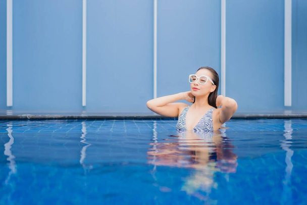 Πορτρέτο όμορφη νεαρή ασιατική γυναίκα χαλαρώστε χαμόγελο γύρω από εξωτερική πισίνα για διακοπές αναψυχής - Φωτογραφία, εικόνα
