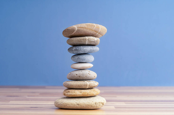 Hand stacking pebbles to make shape of hourglass as a symbol of time management. Concept of meditation, slow down and controlling time. - Foto, afbeelding
