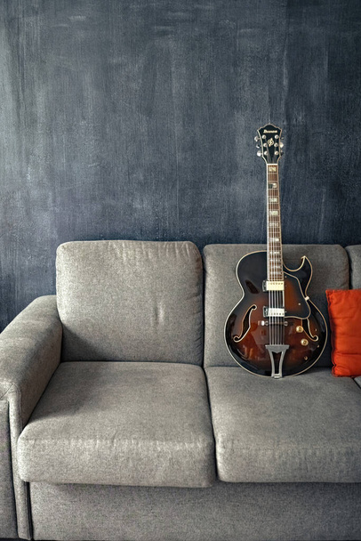 Guitar on the gray sofa, vintage style picture. - Foto, Imagem