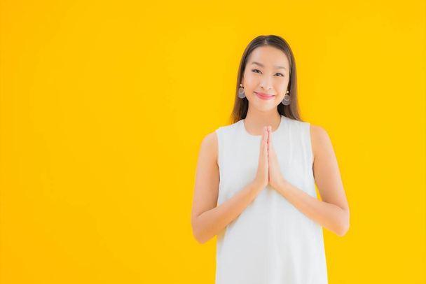 Porträt schöne junge asiatische Frau in Aktion auf gelbem isolierten Hintergrund - Foto, Bild