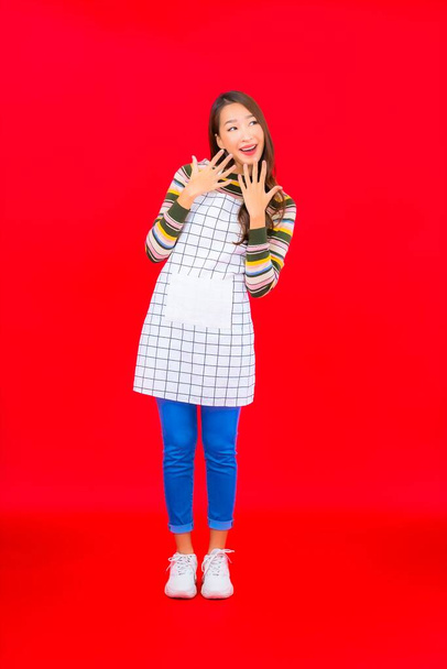 Портрет красива молода азіатка носить фартух на червоному тлі
 - Фото, зображення