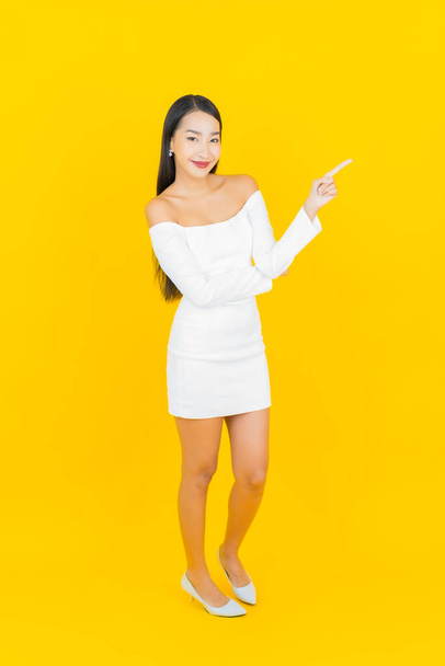 Retrato hermosa joven negocio asiático mujer con sonrisa y acción amarillo fondo - Foto, imagen
