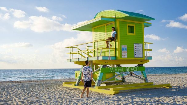 Miami Beach, a couple on the beach at Miami Florida, lifeguard hut Miami Asian women and caucasian men on the beach during sunset. man and woman watching sunrise - 写真・画像