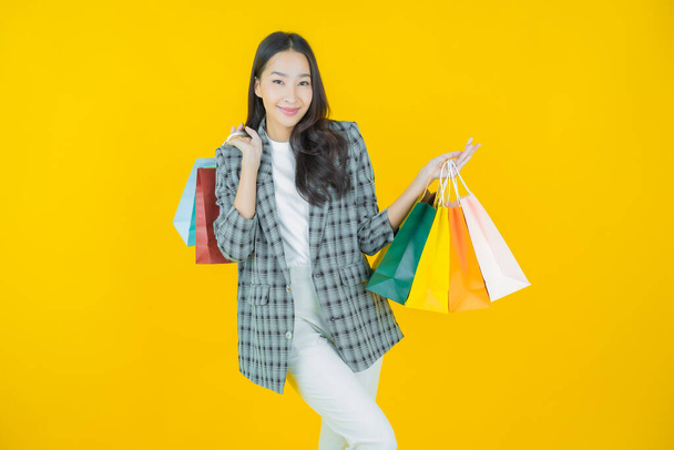Portrait beautiful young asian woman smile with shopping bag on color background - Foto, immagini