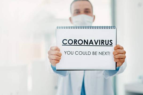This virus doesnt discriminate. a scientist holding a sign with CORONAVIRUS-YOU COULD BE NEXT on it in a laboratory - 写真・画像