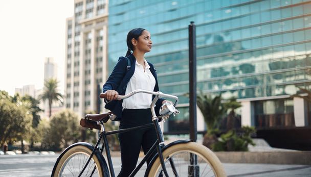 Амбіції рухають вас вперед. молода бізнес-леді, що подорожує з велосипедом через місто
 - Фото, зображення