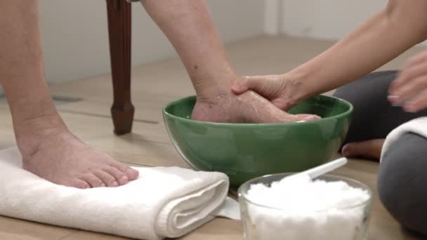 Женщина-сиделка вытирает ноги пожилой женщине полотенцем. - Кадры, видео