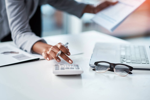 Accountant, businesswoman or banker using calculator, checking paperwork and documents while preparing financial data report in an office. Hands of a woman doing payroll or calculating annual tax. - Photo, image