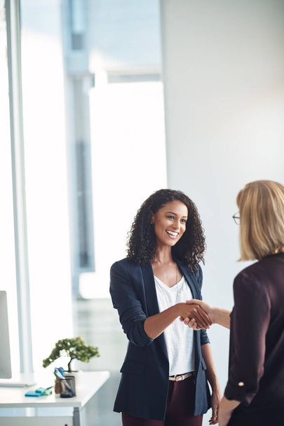 Happy business women shaking hands, meeting and greeting in an office. Confident young professional talking to a manager about a promotion or job performance. Hr congratulating an ambitious employee. - Photo, image