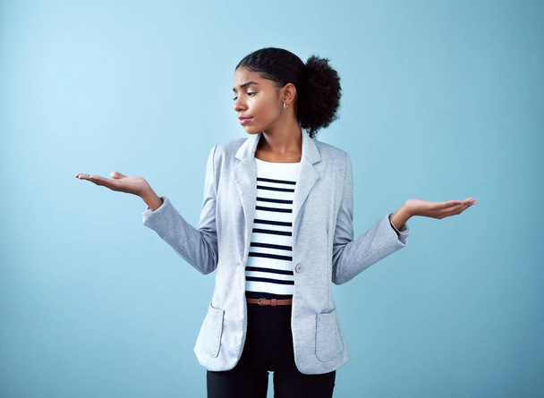 Профессиональный черный корпоративный бизнес женщина делает жест руки для решения, выбора и баланса, стоя на фоне синей студии в одиночку. Один африканский менеджер выбирает между идеями. - Фото, изображение