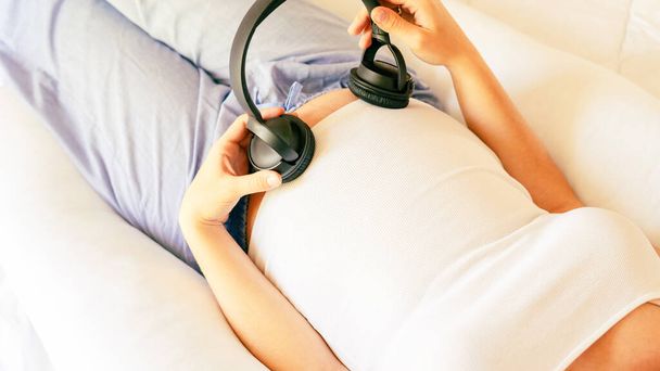 Pregnant music woman listen. Mother belly listen headphones sound. Pregnancy woman listening to music. Concept maternity, pregnancy, childbirth - Fotó, kép