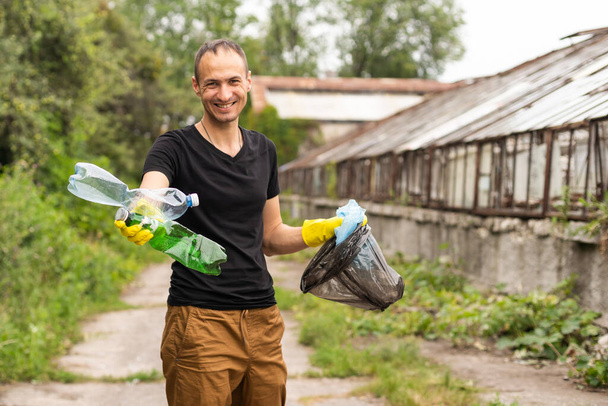 young man picking up trash outdoor. close up. - Фото, зображення